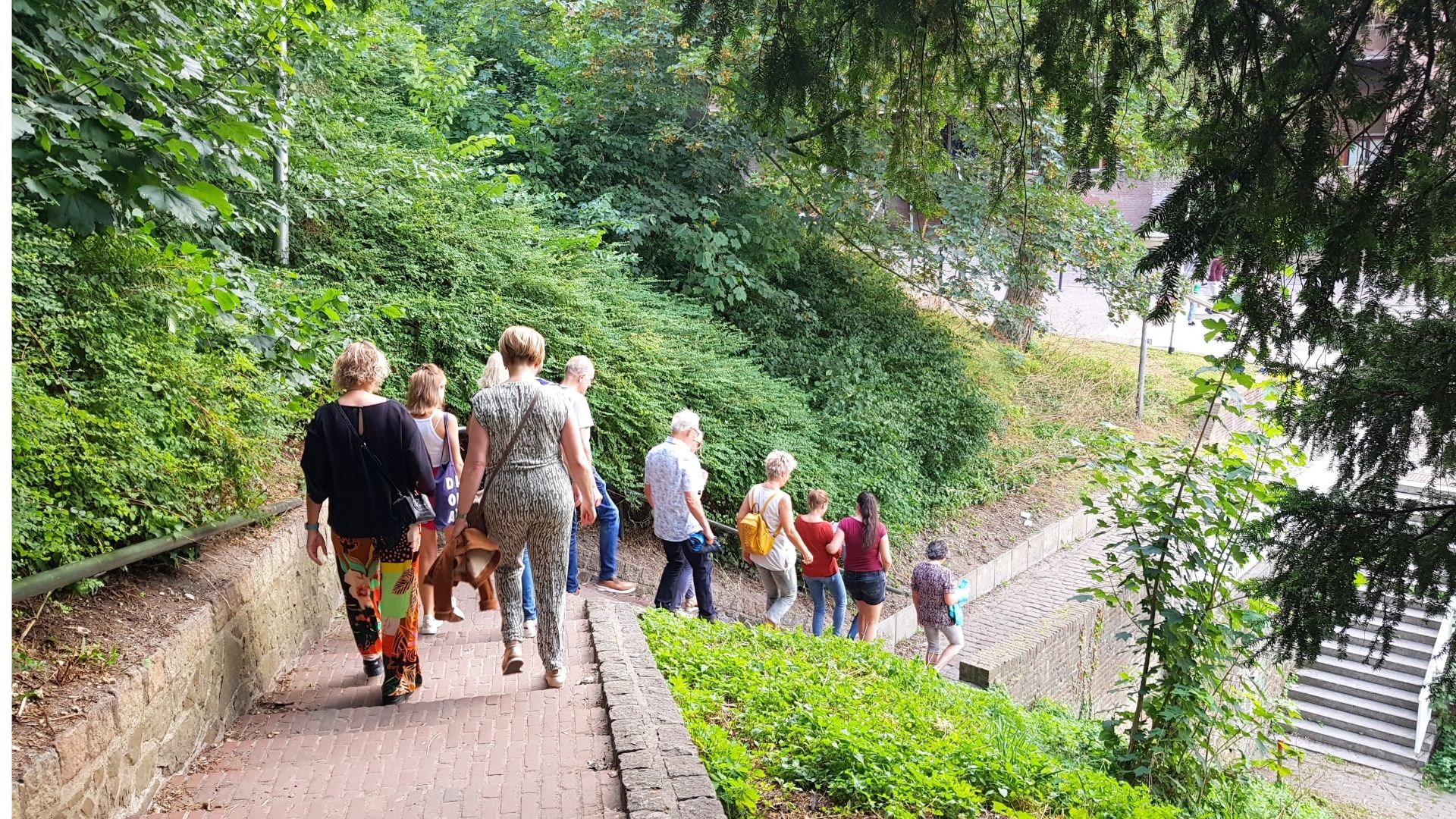 Een groep onder leiding van een gids daalt de trappen af van het Valkhof in Nijmegen